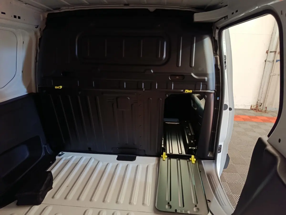 Vue intérieure arrière du Peugeot Partner blanc montrant la cloison pleine et l'espace de chargement vide.