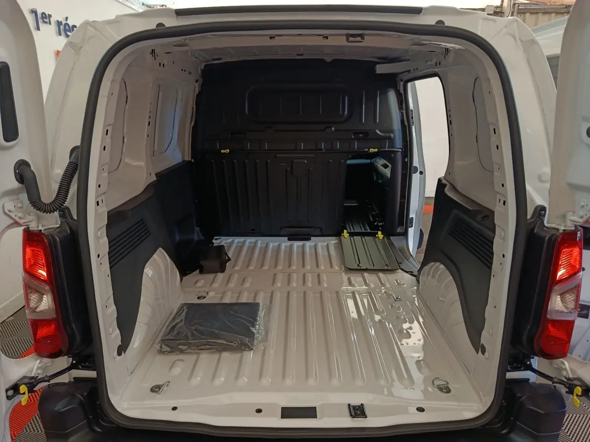 Vue arrière du Peugeot Partner blanc 2025, montrant l'espace de chargement vide avec cloison pleine noire.