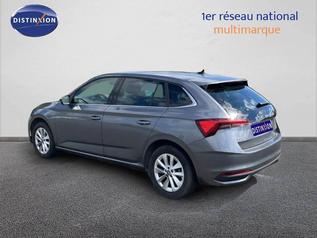 Vue 3/4 arrière droite d'une Skoda Scala gris magnétique métal, avec feux arrière allumés et jantes argentées.