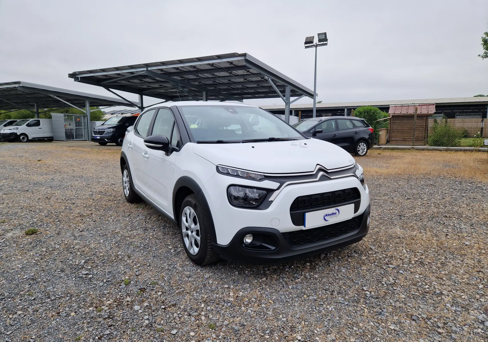Citroën C3 Société blanche vue en 3/4 avant droit, avec calandre noire et protections de bas de caisse noires.