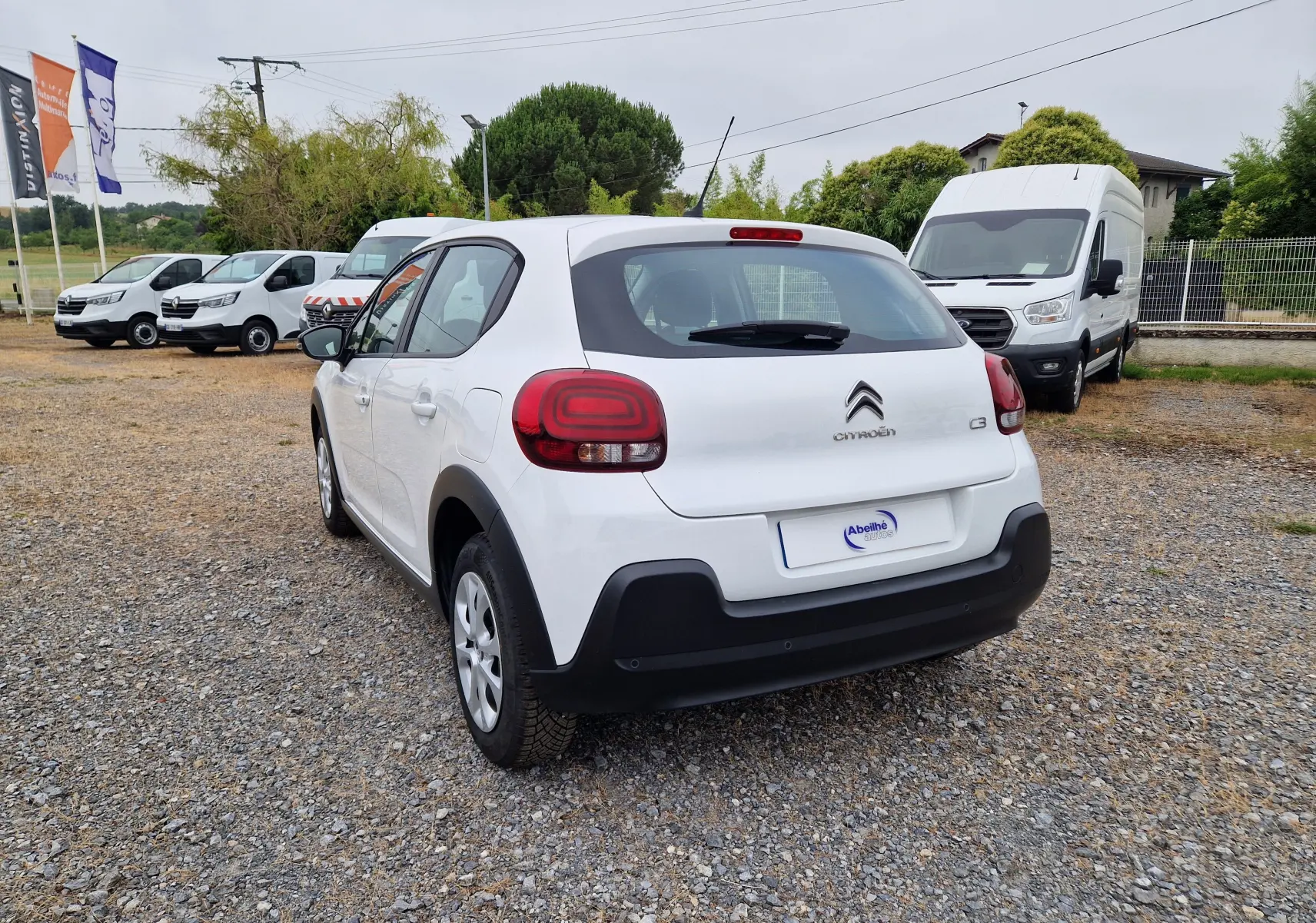 Vue 3/4 arrière droite d'une Citroën C3 Société blanche avec feux arrière distinctifs et pare-chocs noir.