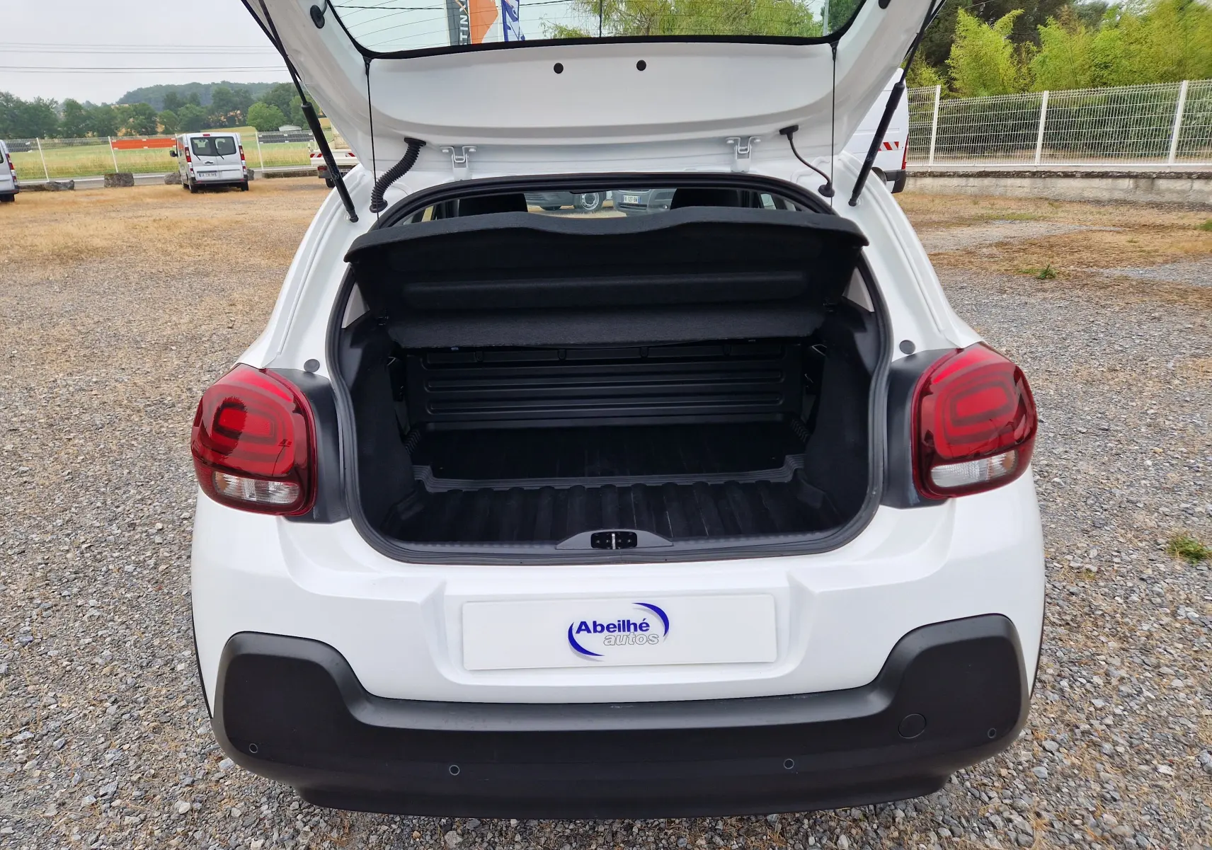 Vue arrière d'une Citroën C3 Société blanche de 2021 avec coffre ouvert, feux arrière rouges et pare-chocs noir.