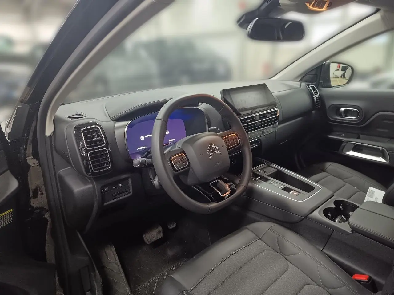 Vue intérieure côté conducteur du Citroën C5 Aircross Hybrid noir Perla, avec tableau de bord numérique et console centrale moderne.