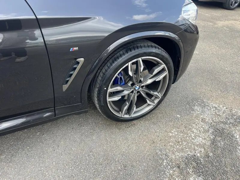 Gros plan sur la roue avant droite du BMW X3 M40iA Sophistograu métallisé avec étrier de frein bleu et jante 21 pouces rayons en V.