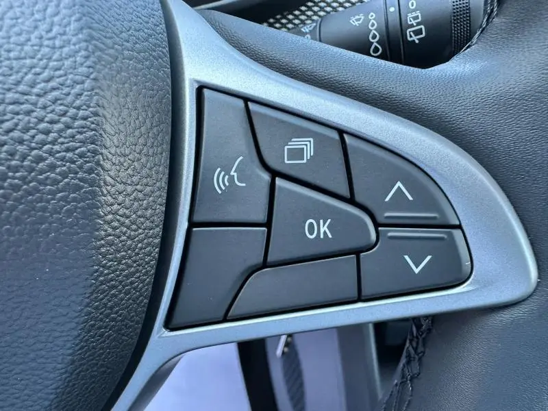 Gros plan sur les commandes noires du volant côté gauche de la Dacia Sandero beige Safari 2025 Stepway.