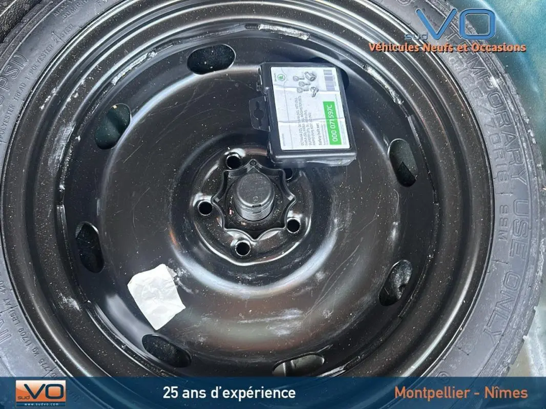 Gros plan sur la roue de secours noire du SEAT Ateca bleu foncé, avec étiquette et marquages visibles sur le pneu.