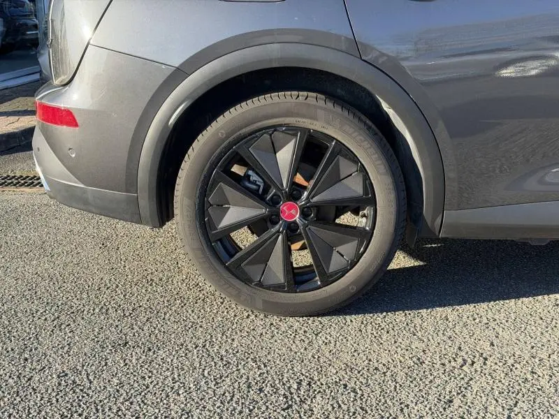 Gros plan sur la roue arrière gauche du DS7 E-TENSE 225ch Performance Line 2024 en Gris Titane avec jante noire distinctive.