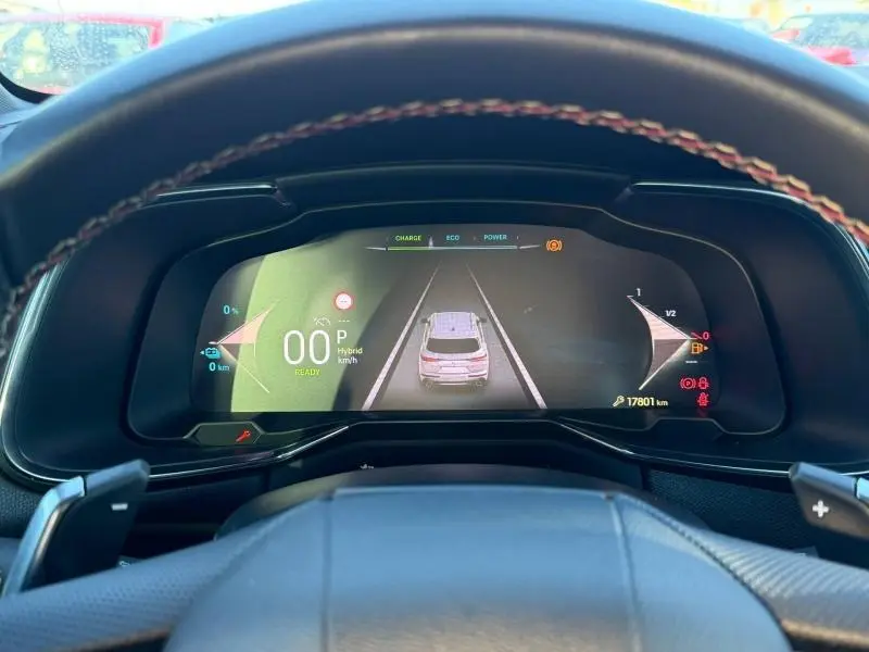 Vue rapprochée du tableau de bord numérique du DS7 E-TENSE 225ch gris titane, affichant l'assistance de conduite et l'autonomie hybride.