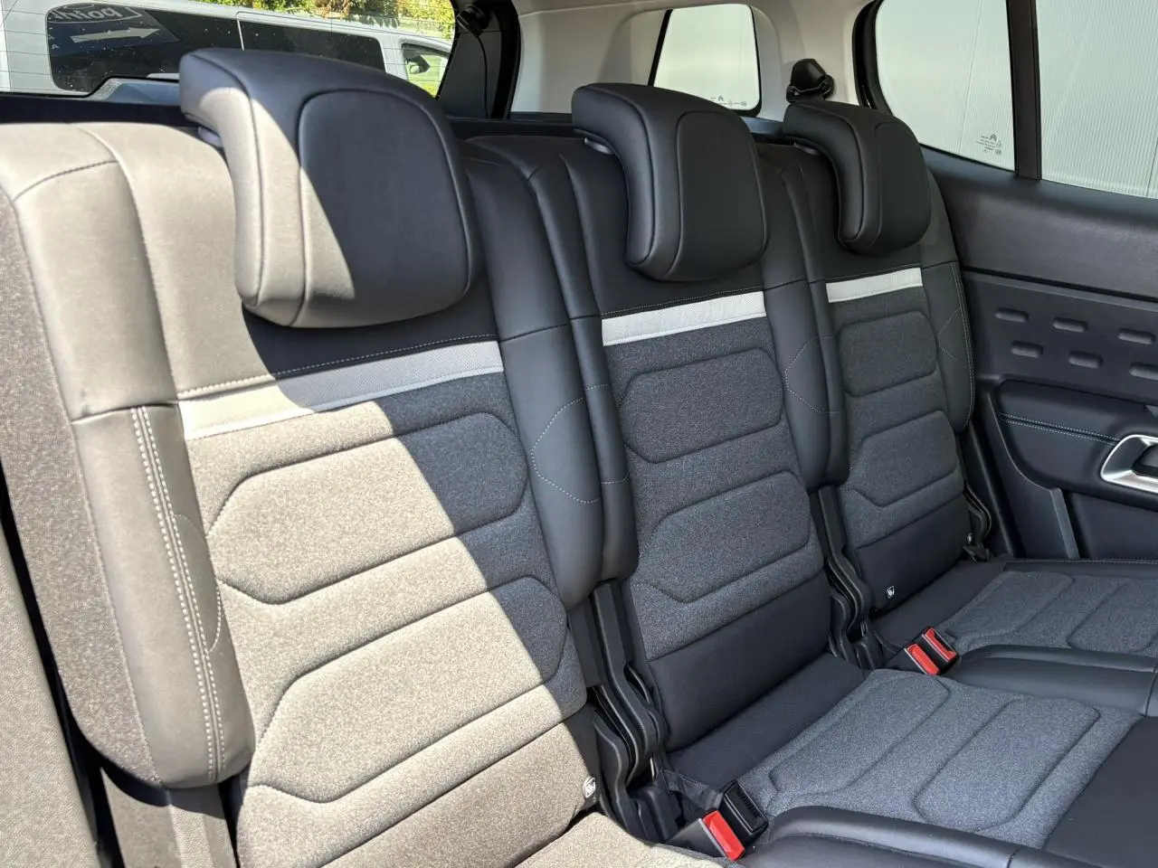 Vue rapprochée des trois sièges arrière indépendants gris et noirs du Citroën C5 Aircross Hybrid 2025, avec appuis-tête réglables.