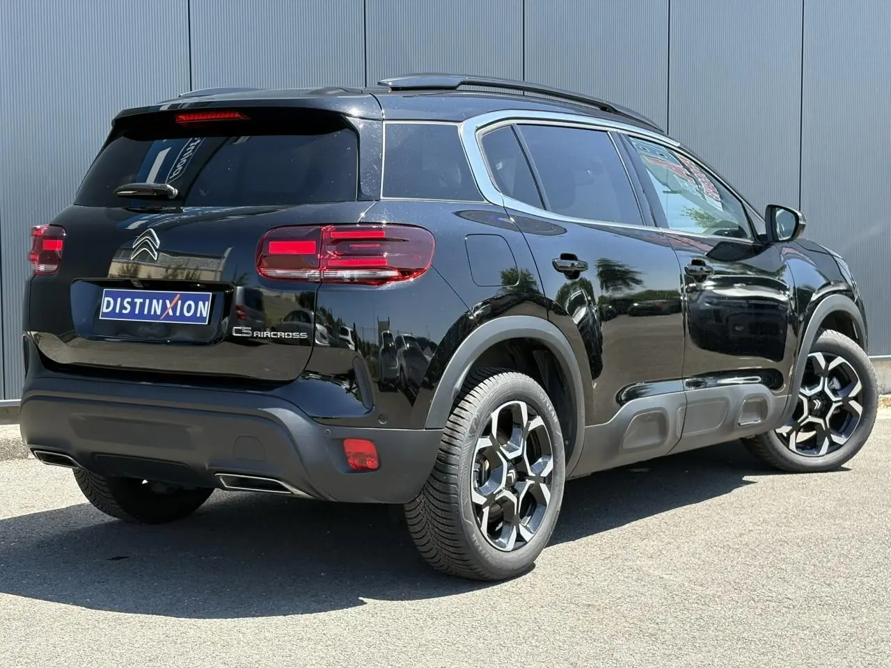 Vue 3/4 arrière droite du Citroën C5 Aircross Hybrid noir Perla avec jantes alliage et hayon électrique visible.