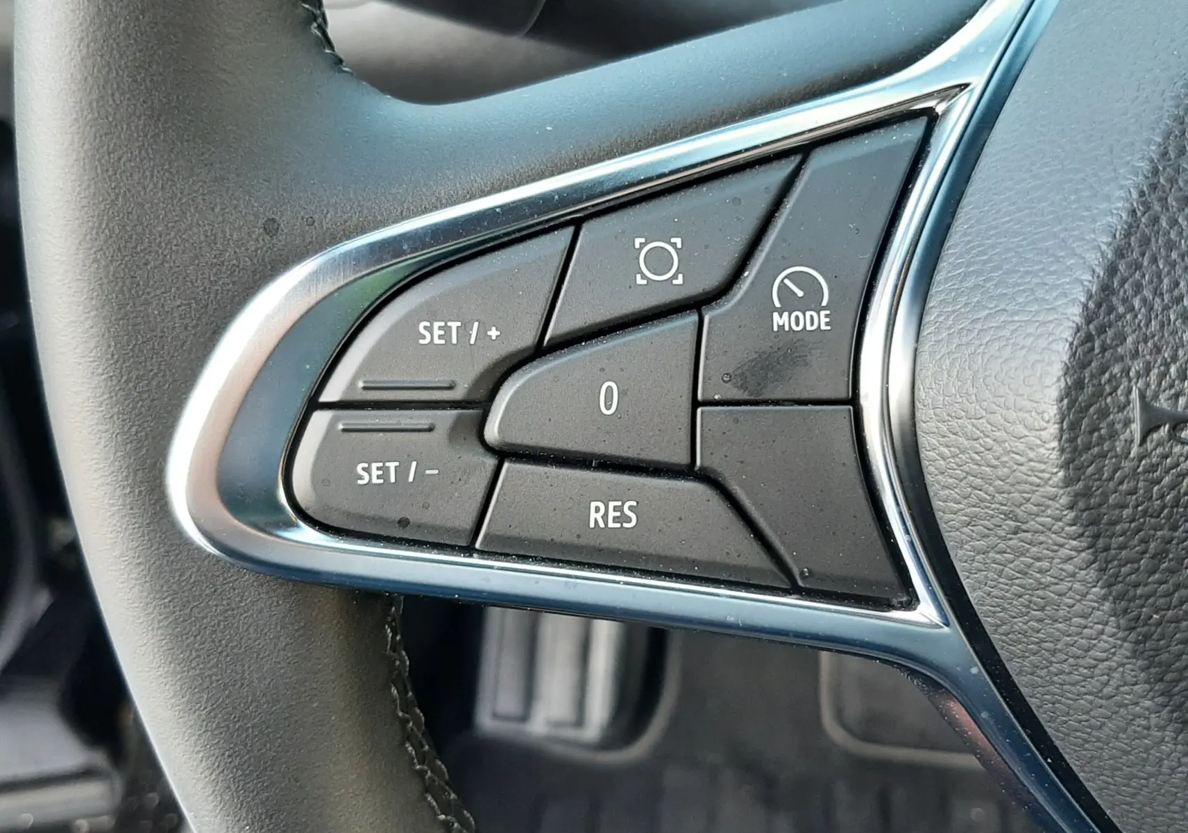 Gros plan sur les commandes de régulateur de vitesse au volant noir du Renault Captur 2024.