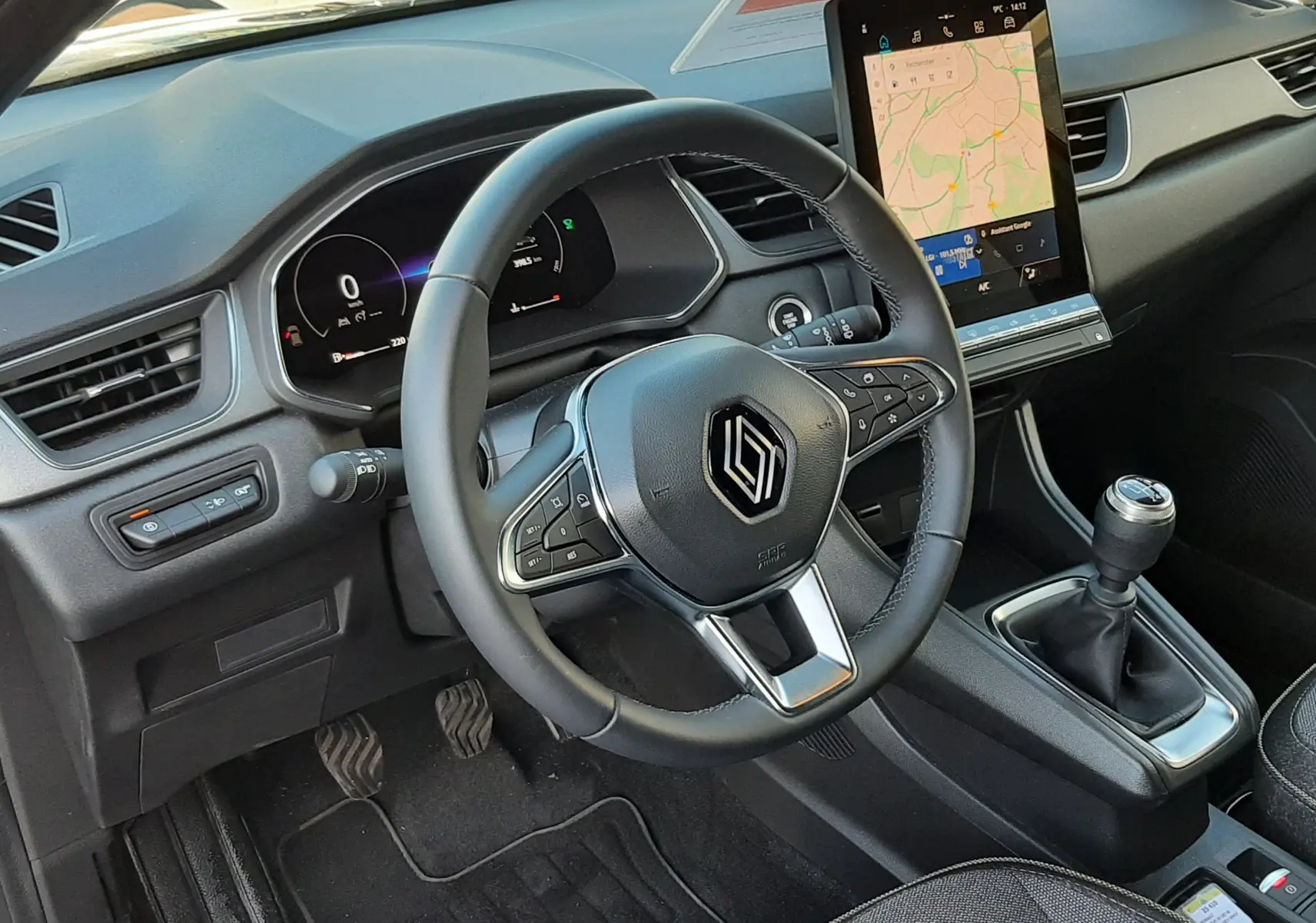 Intérieur noir du Renault Captur 2024, vue du poste de conduite avec volant multifonction et levier de vitesse manuel.