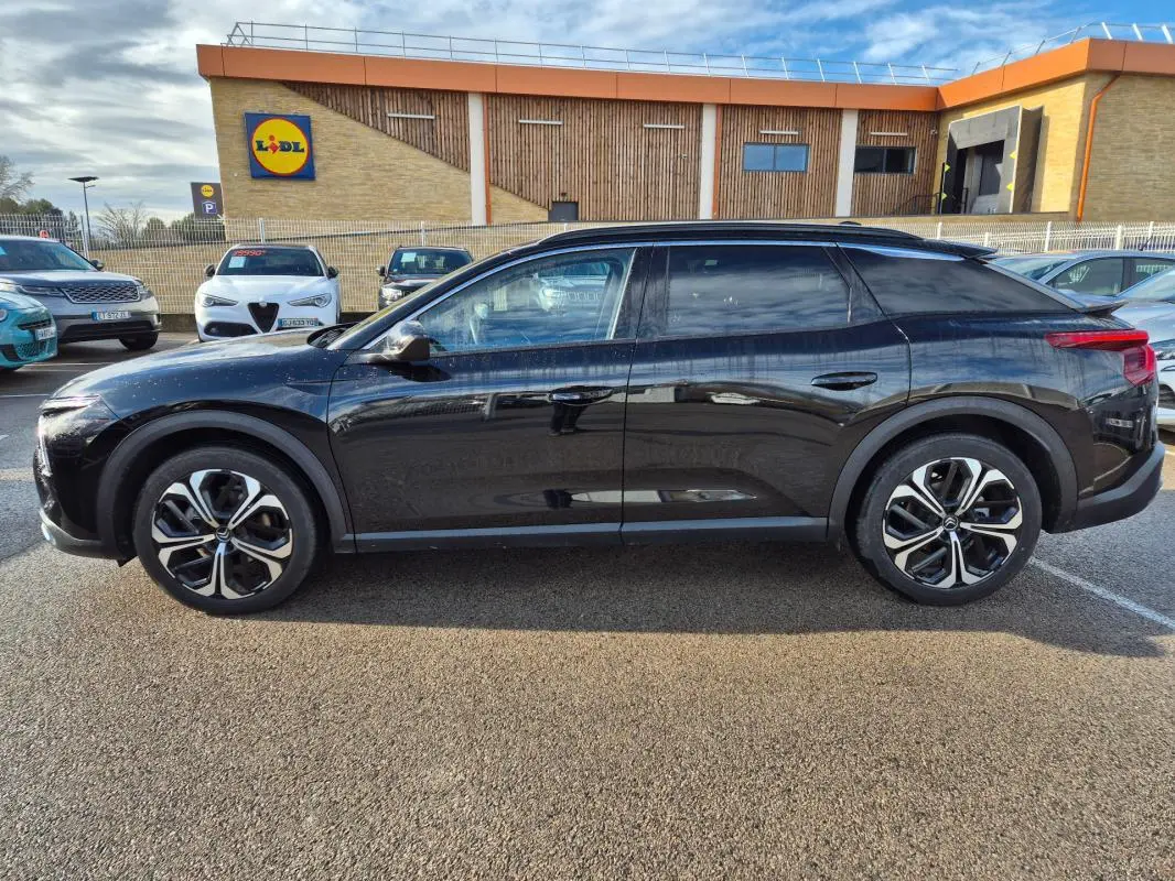 Vue latérale droite d'une Citroën C5 X noire 2024 avec jantes alliage 19 pouces, stationnée en extérieur.