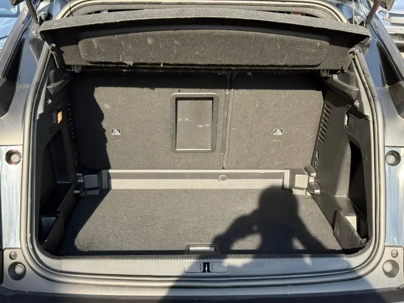 Vue arrière du coffre ouvert du Peugeot 3008 2024 Bleu Célèbes, montrant l'espace de rangement et le hayon relevé.