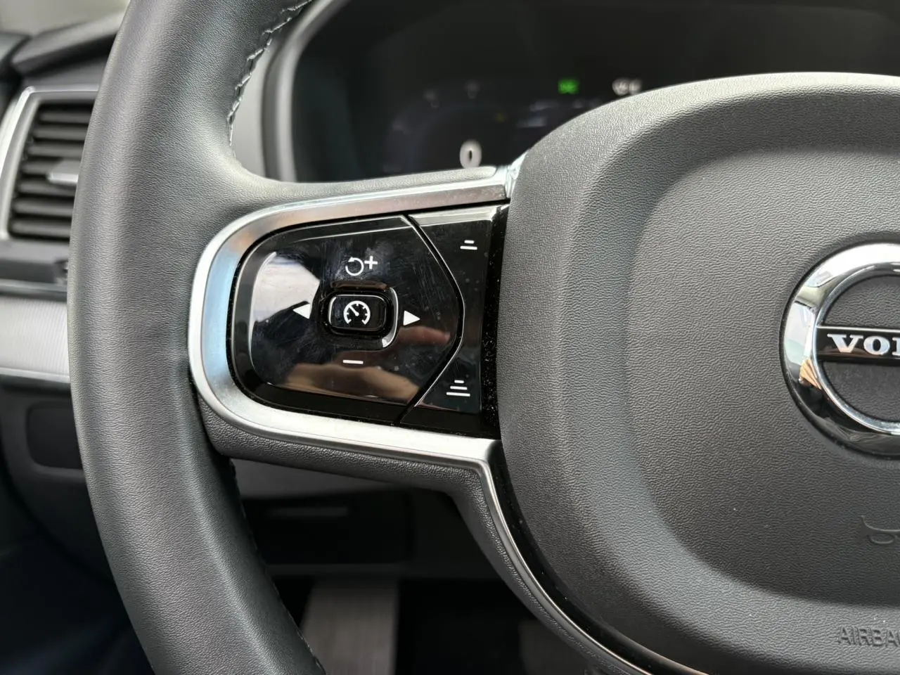Gros plan sur la partie gauche du volant noir du Volvo XC90 T8 AWD 2024 avec commandes intégrées et logo central.