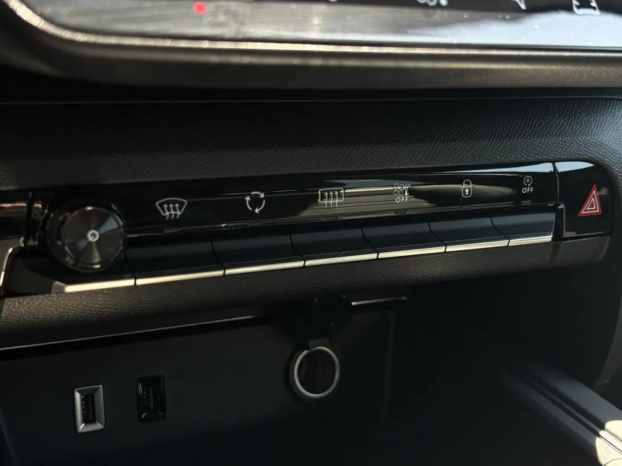 Gros plan sur la console centrale noire du Citroën C5 Aircross Hybrid 2025, avec boutons de commande et prises USB visibles.