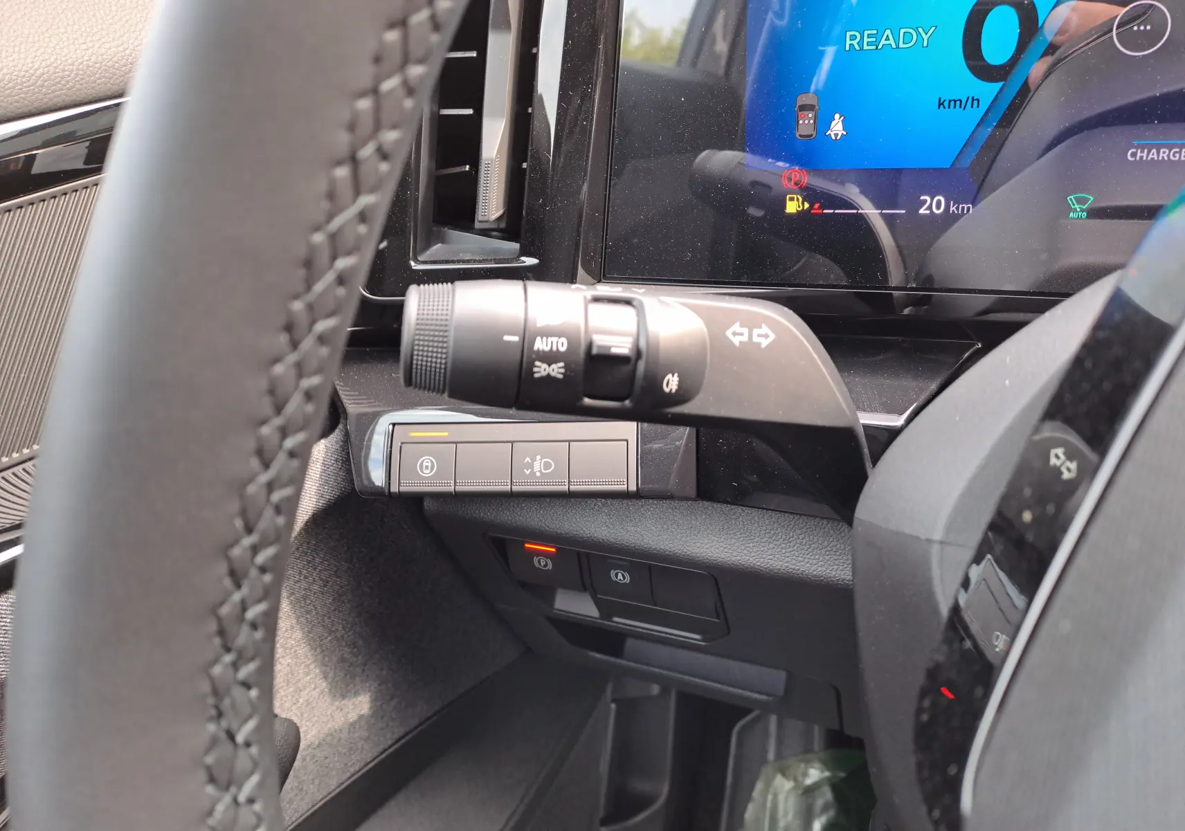 Gros plan sur la commande des clignotants et tableau de bord numérique bleu du Renault Austral gris schiste, côté gauche du volant.