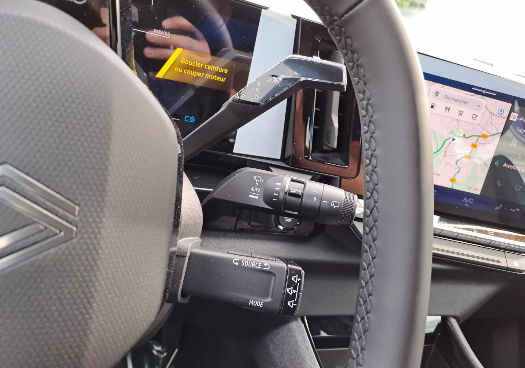 Gros plan sur le volant et la console centrale du Renault Austral gris schiste, avec écran tactile et commandes au volant visibles.