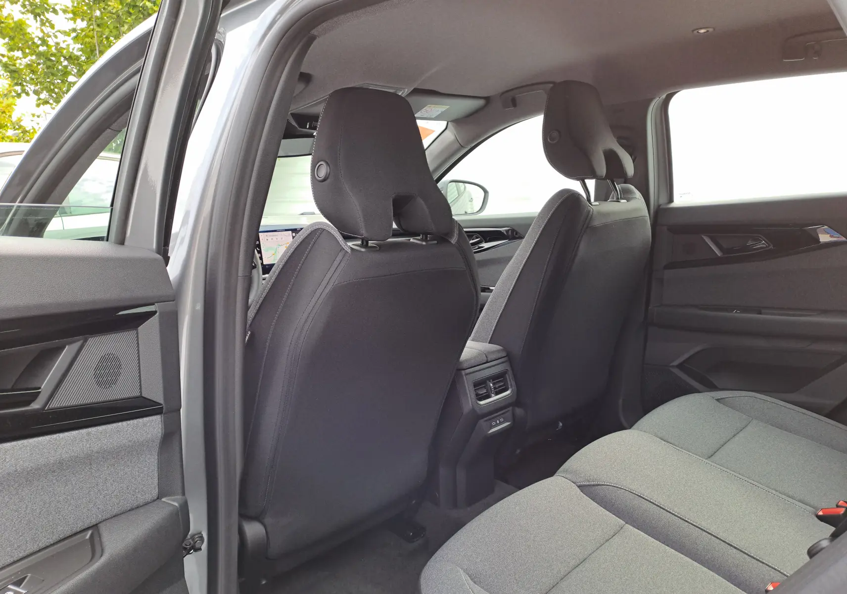 Intérieur arrière du Renault Austral gris schiste 2025, vue côté gauche montrant les sièges tissu noir et les aérateurs centraux.