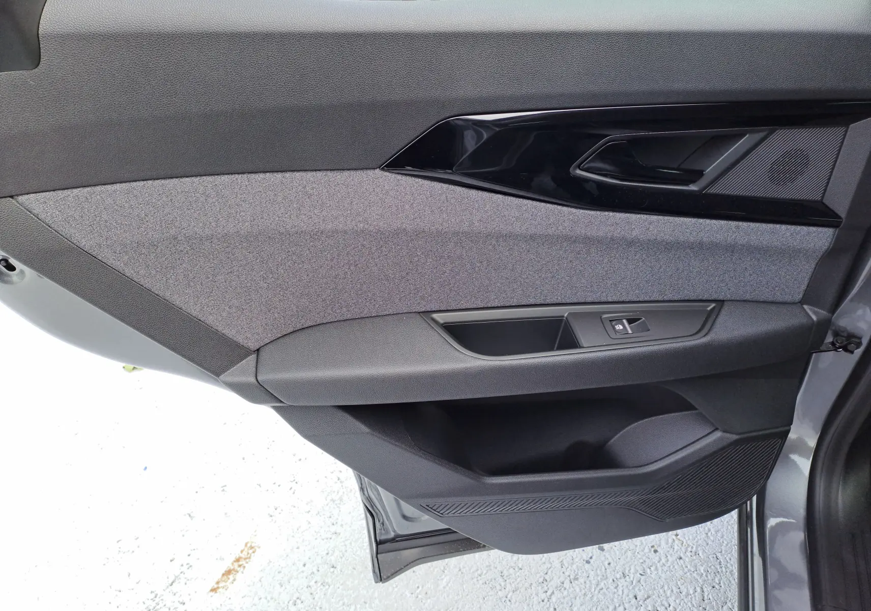 Vue rapprochée de la porte avant gauche du Renault Austral gris schiste, avec garniture tissu gris et commandes de vitre.