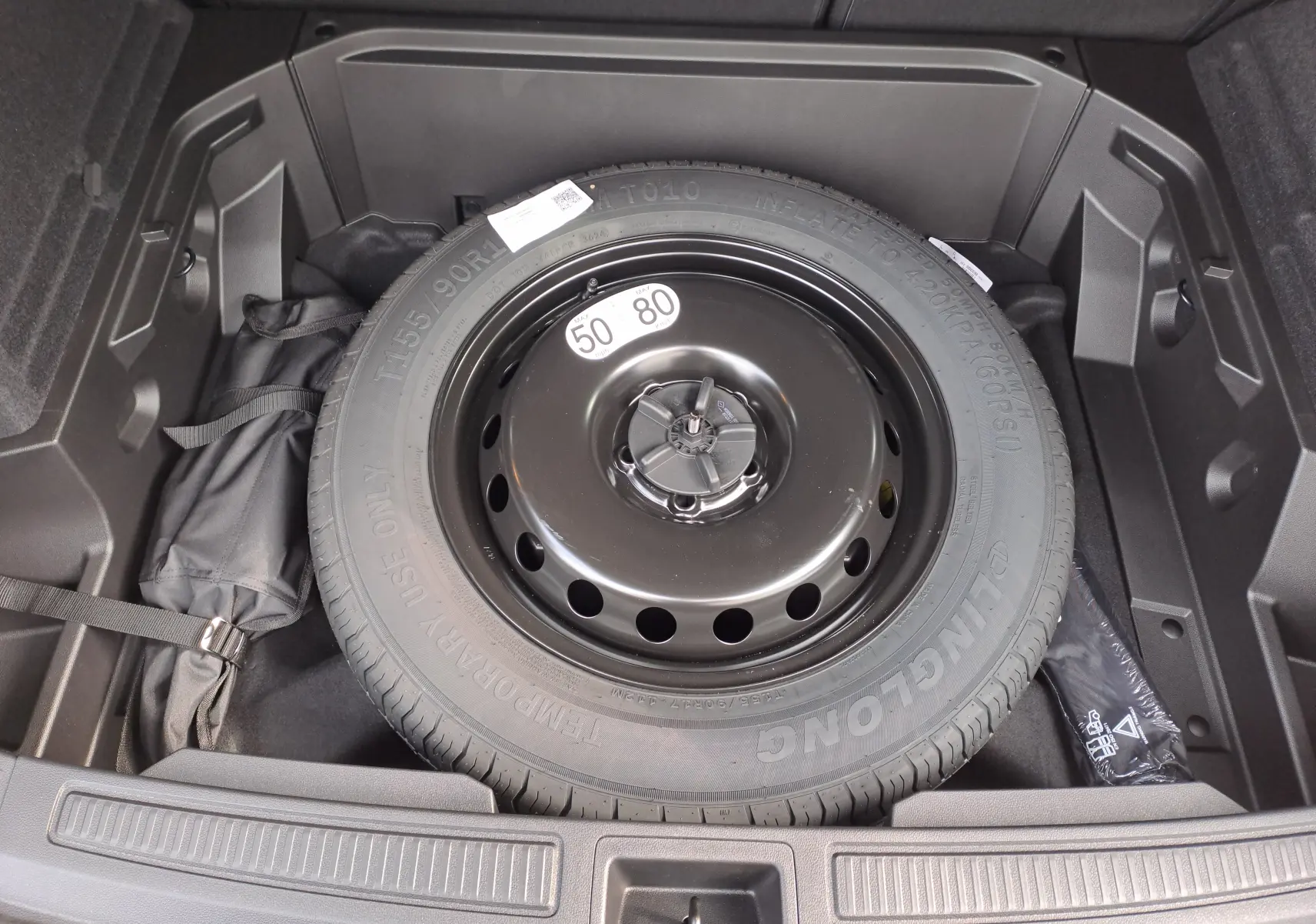 Vue rapprochée de la roue de secours noire dans le coffre du Renault Austral gris schiste 2025 hybride.