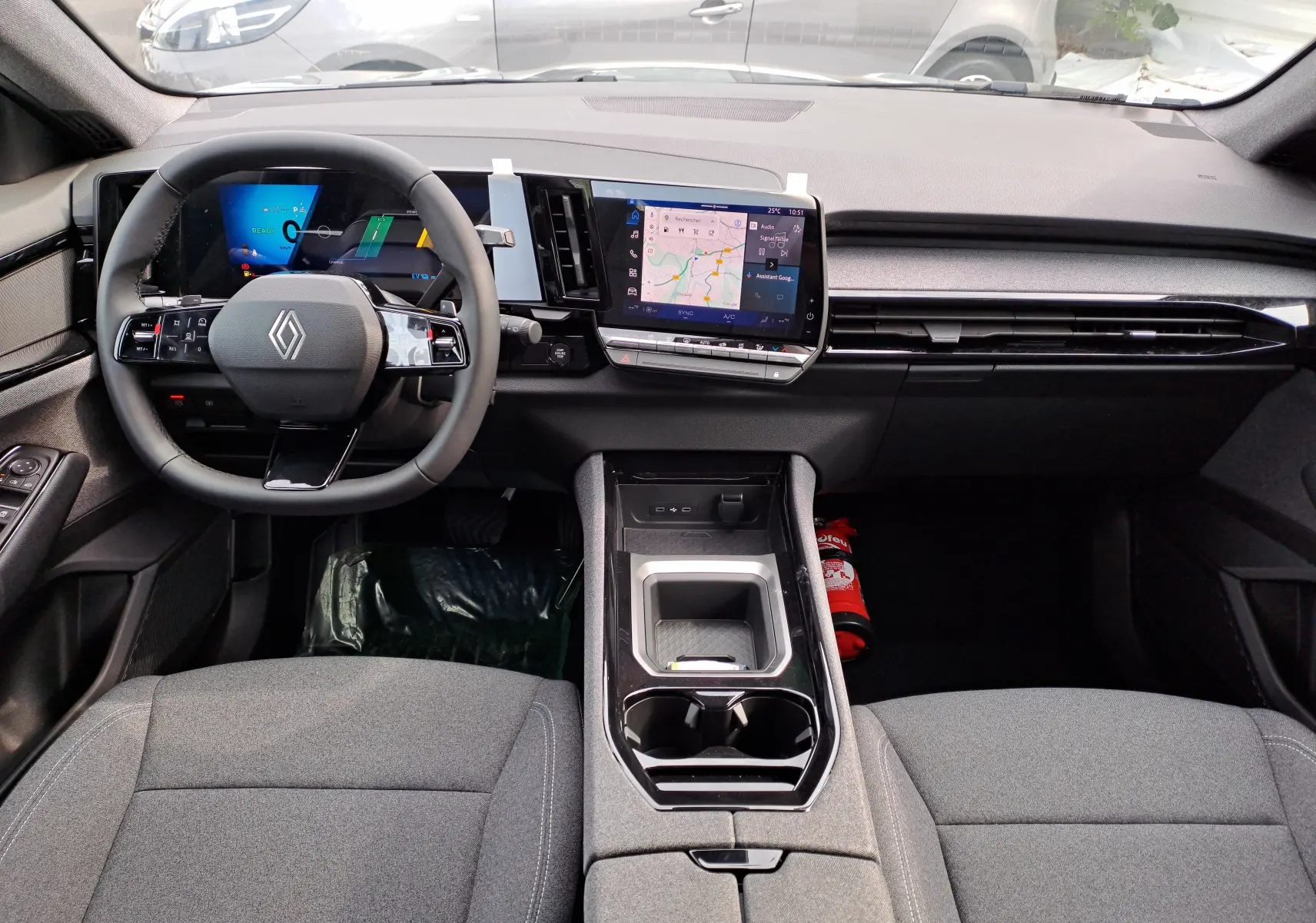 Vue intérieure du tableau de bord du Renault Austral gris schiste, avec volant multifonctions et écran tactile central affichant la navigation.