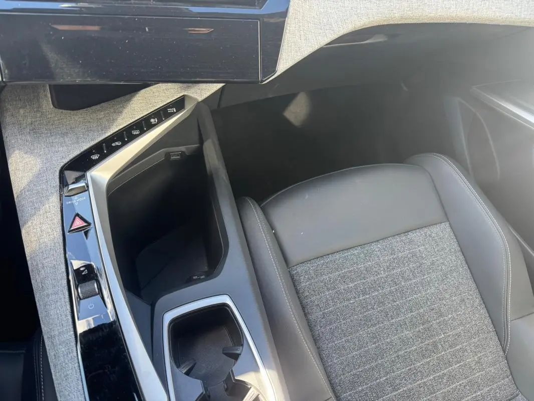 Vue plongeante sur la console centrale et siège avant gris tissu et cuir du Peugeot 5008 Hybrid 145 e-DCS6 Allure 2025.