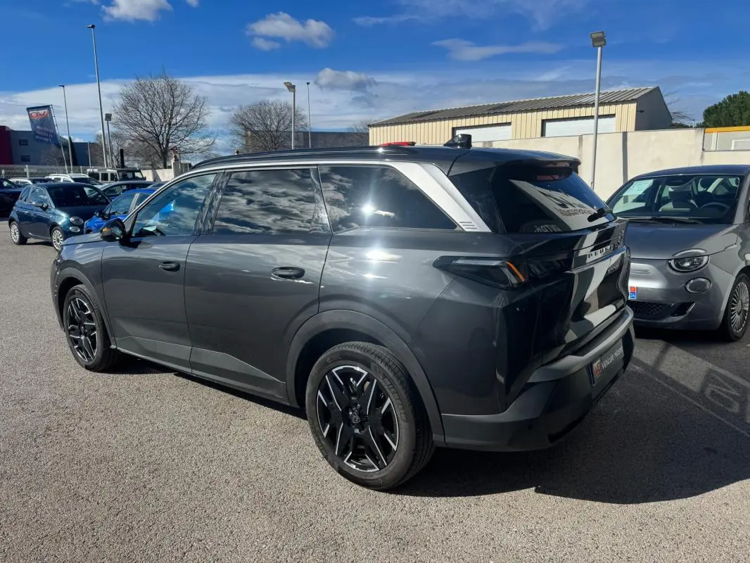 Peugeot 5008 Hybrid gris vue 3/4 arrière droit, jantes alliage noires 19 pouces, vitres teintées et toit noir.