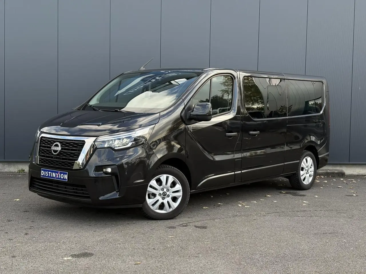 Nissan Primastar noir métal vu en 3/4 avant droit, avec vitres latérales teintées et jantes alliage.