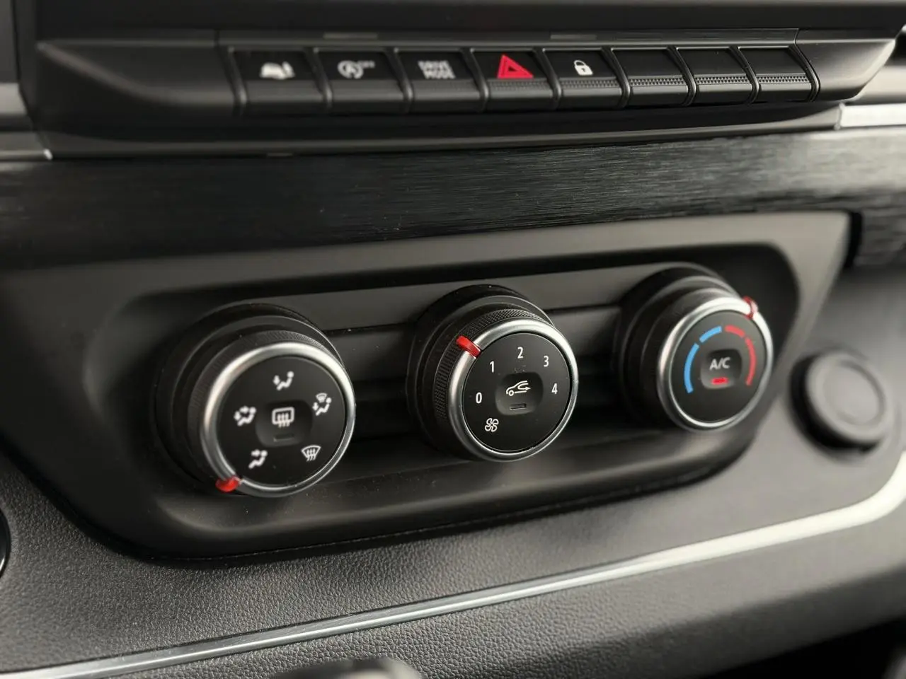 Gros plan sur les commandes de climatisation noires du tableau de bord du Nissan Primastar 2025, avec réglages ventilateur et A/C.