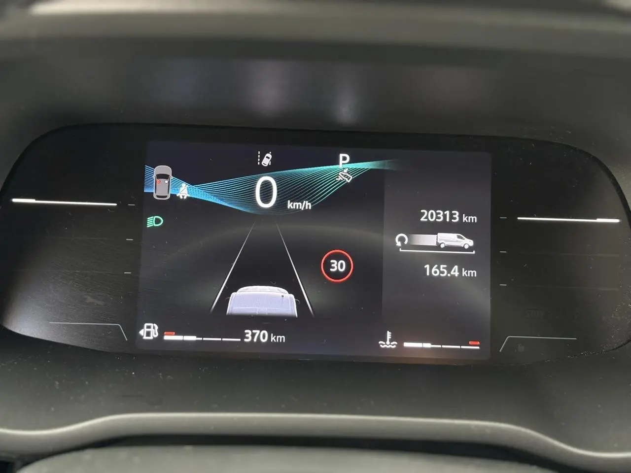 Tableau de bord numérique du Nissan Primastar 2025 affichant la vitesse, autonomie et alertes, vue frontale rapprochée.