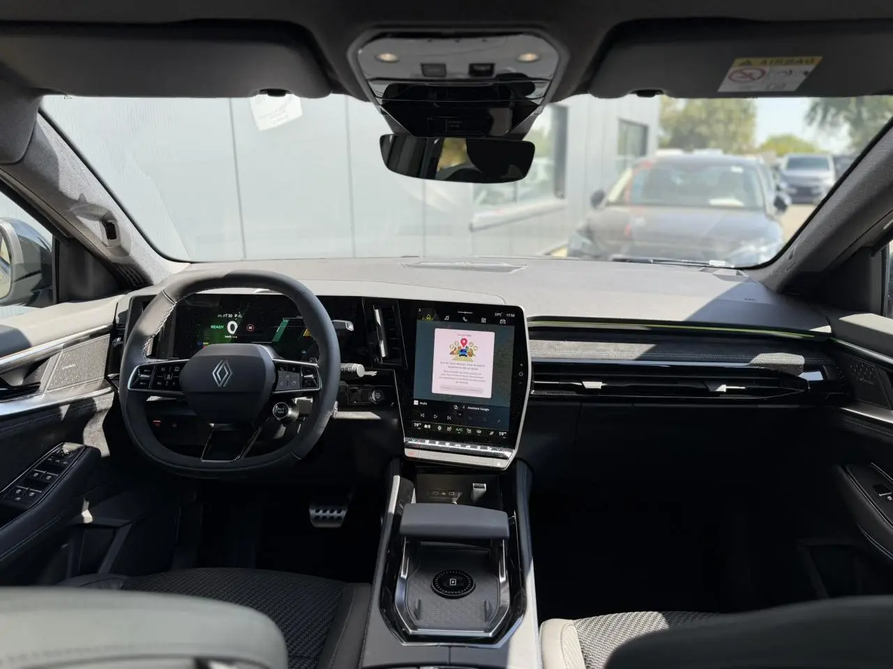 Vue intérieure avant du Renault Austral E-Tech hybride, tableau de bord noir avec écran tactile vertical et volant multifonction.