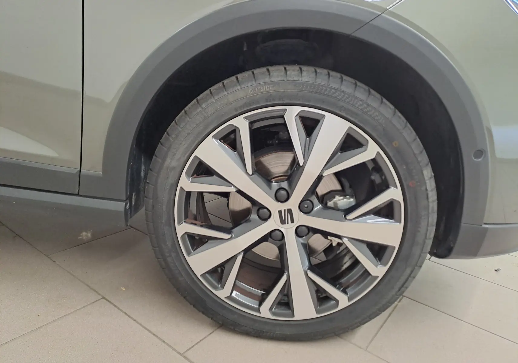 Gros plan sur la roue avant droite du SEAT Arona gris falaise, jante alliage 18'' au design moderne bicolore.