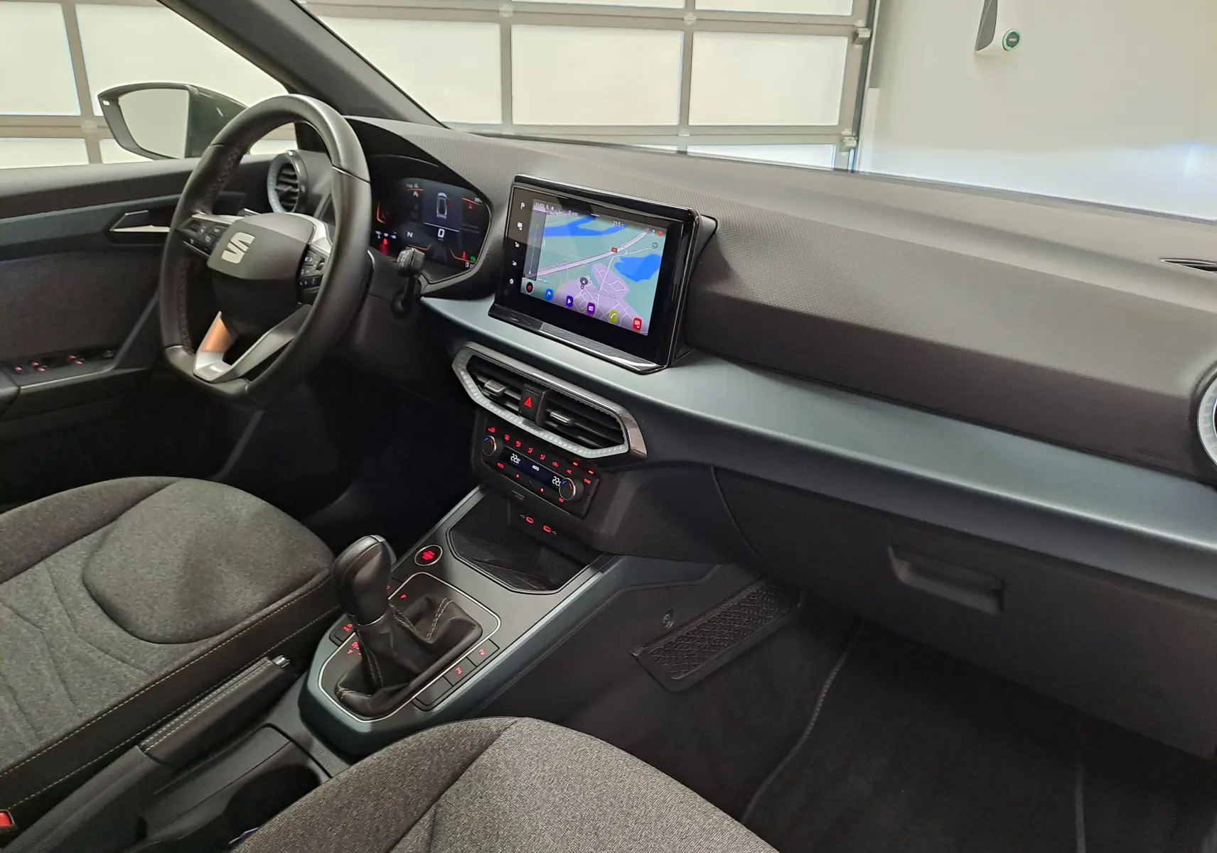 Vue intérieure côté conducteur du SEAT Arona 2024 avec tableau de bord moderne et écran tactile central.