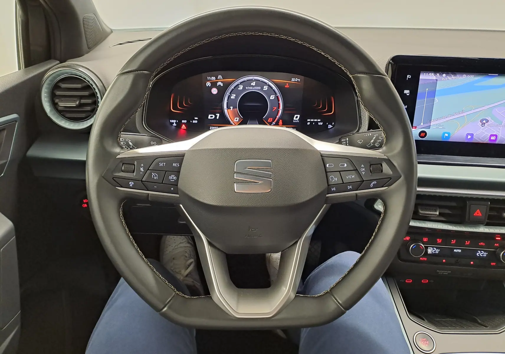 Vue intérieure centrée sur le volant multifonction du SEAT ARONA 2024 avec tableau de bord numérique et écran tactile.