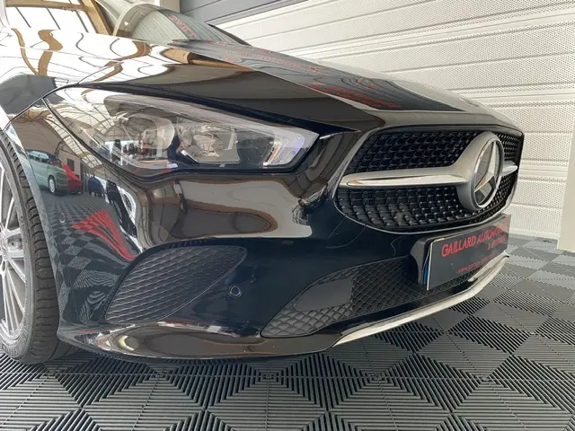 Gros plan sur l’avant droit noir brillant d’une Mercedes CLA Shooting Brake avec calandre étoile et phares LED.