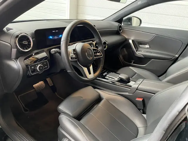 Intérieur noir de la Mercedes CLA 200 d 2021 vu côté conducteur, avec volant cuir multifonctions et écran tactile digital.