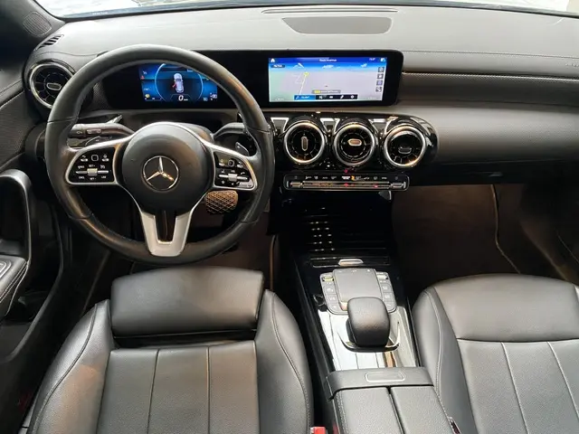 Vue intérieure avant de la Mercedes Classe CLA Shooting Brake noire, tableau de bord moderne avec écran tactile et volant cuir multifonctions.