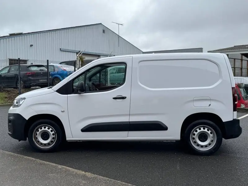 Profil côté gauche d'un utilitaire Citroën Berlingo Fourgon blanc Banquise avec porte latérale et enjoliveurs acier.