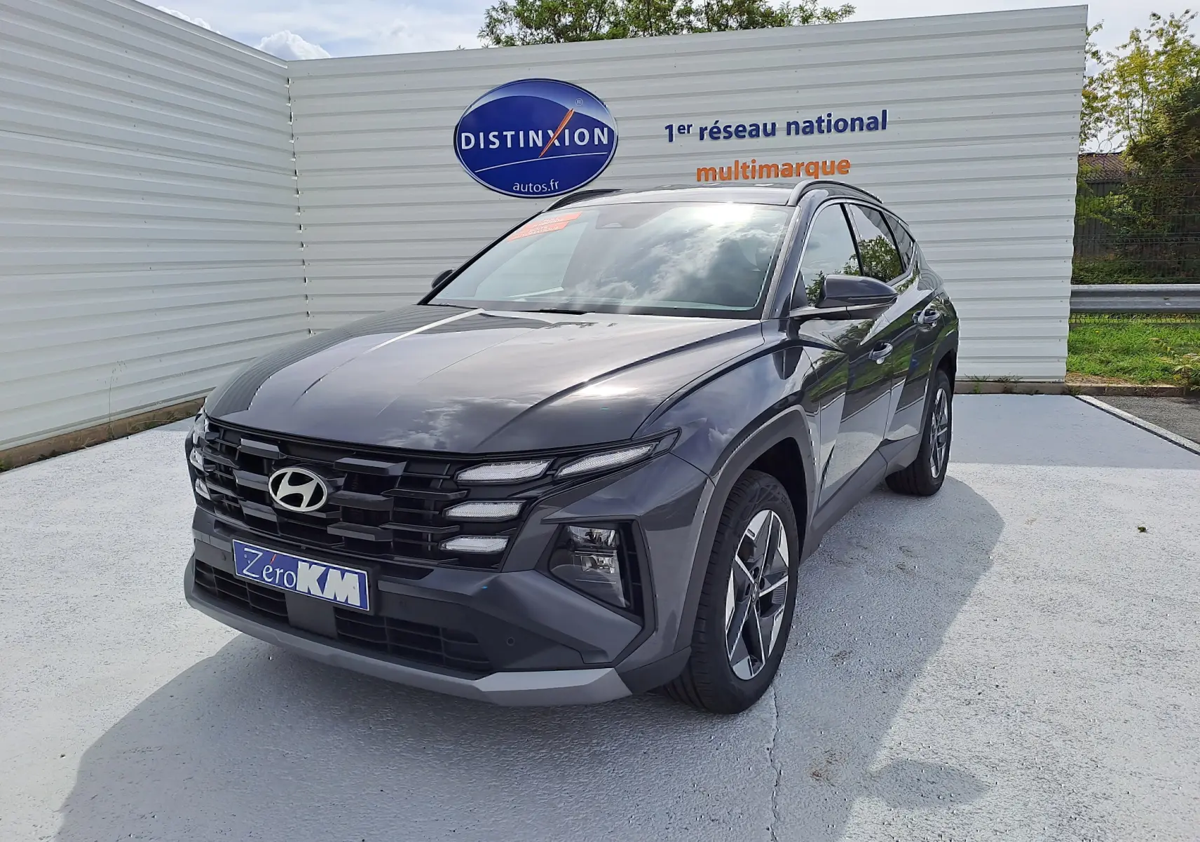 Hyundai Tucson 2025 gris Ecotronic vu en 3/4 avant droit avec calandre noire et jantes bi-ton.