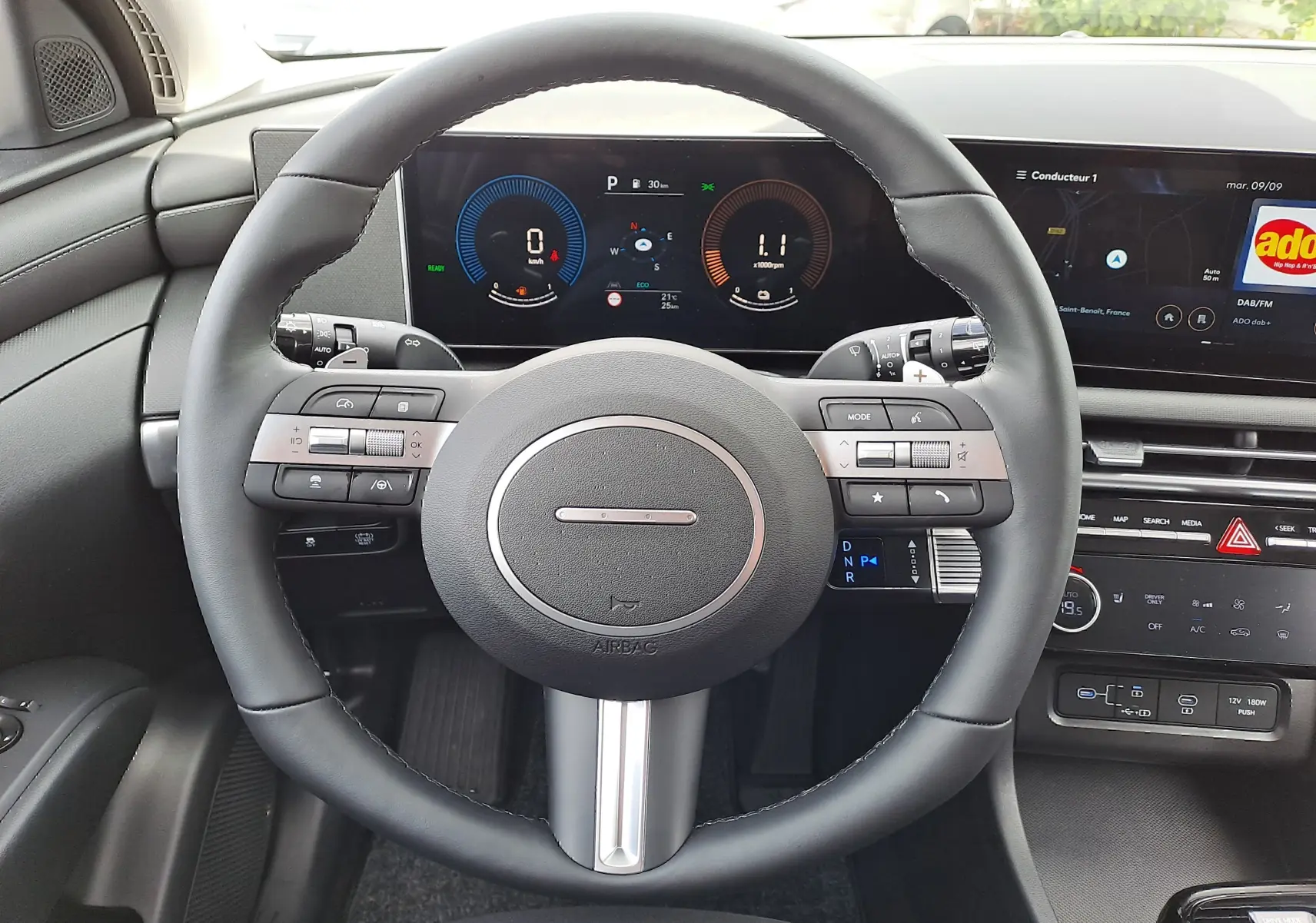 Vue intérieure centrée sur le volant noir du Hyundai Tucson 2025 avec tableau de bord numérique et écran tactile.