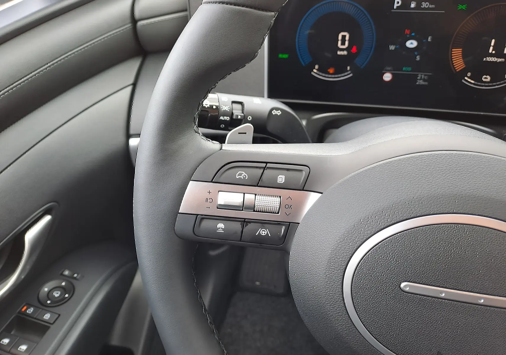 Gros plan sur le volant noir et les commandes multifonctions du Hyundai Tucson 2025, avec tableau de bord numérique en arrière-plan.