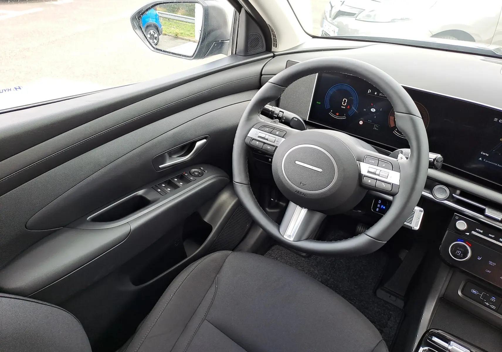 Intérieur noir du Hyundai Tucson 2025, vue côté conducteur sur le volant et tableau de bord numérique moderne.