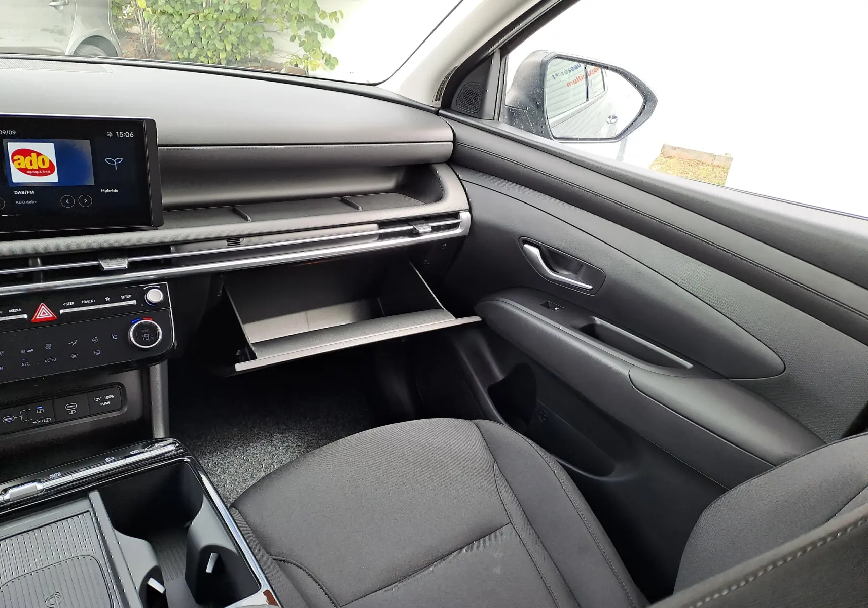 Intérieur noir du Hyundai Tucson 2025, vue côté passager avec boîte à gants ouverte et tableau de bord moderne.