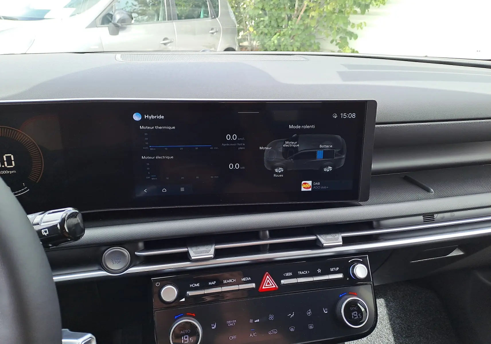 Vue intérieure du tableau de bord du Hyundai Tucson 2025 gris, écran tactile affichant les données hybrides et commandes climatisation.