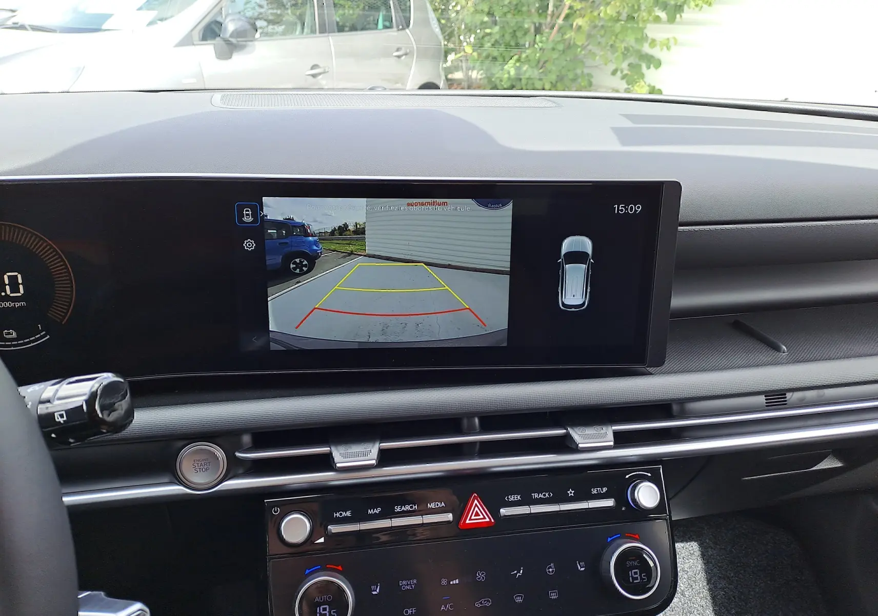 Vue intérieure du tableau de bord du Hyundai Tucson 2025, écran affichant la caméra de recul et commandes climatisation.