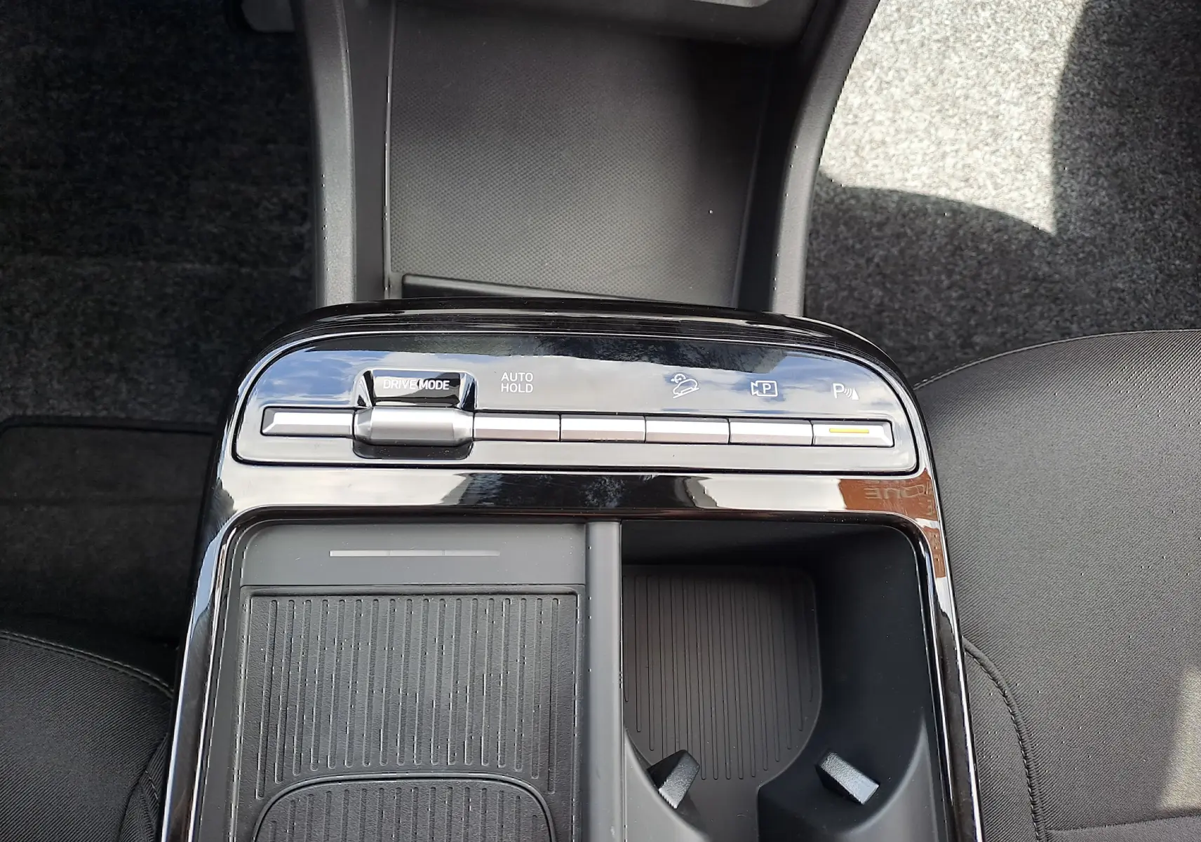 Vue plongeante sur la console centrale noire du Hyundai Tucson 2025, avec commandes de mode de conduite et porte-gobelets.