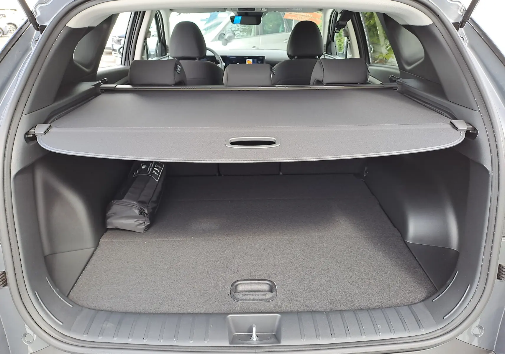Coffre ouvert du Hyundai Tucson 2025 gris Ecotronic, vue arrière montrant la plage arrière et l'habitacle noir.