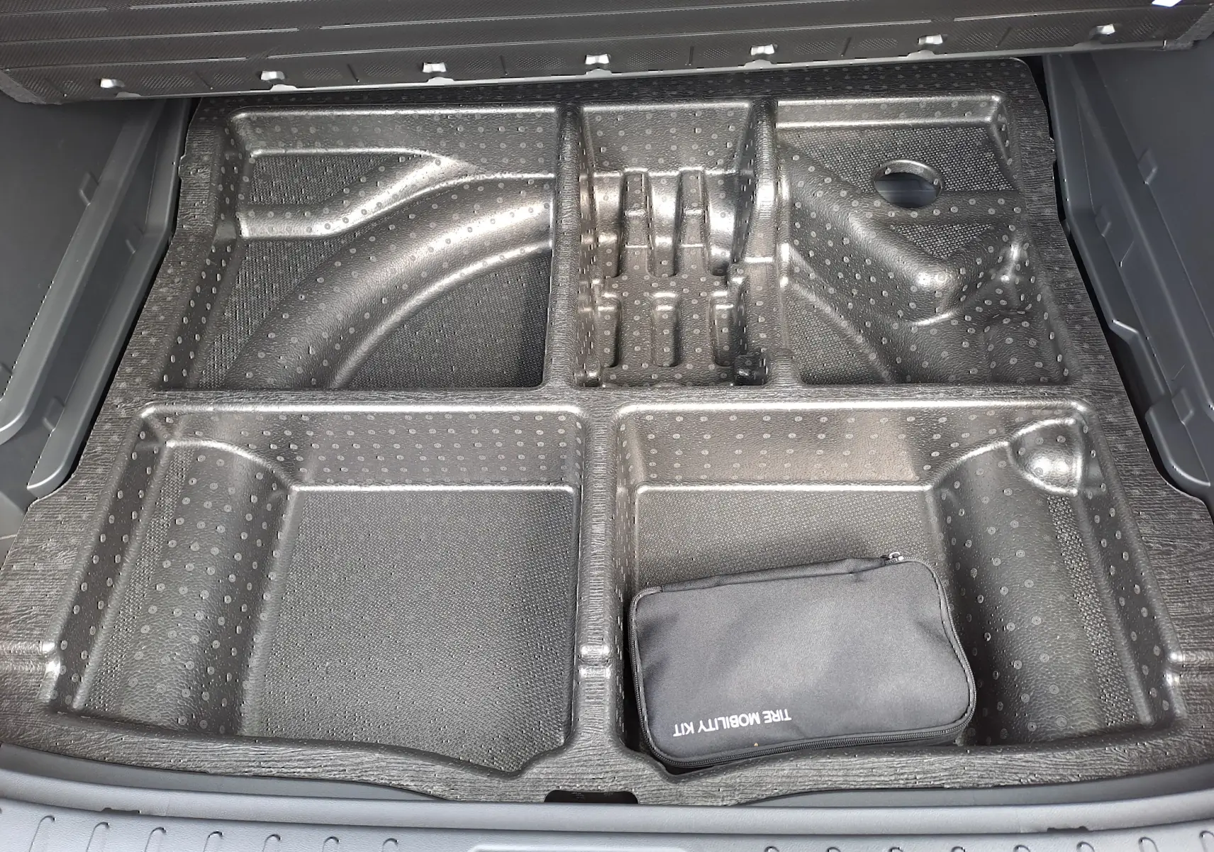 Rangement compartimenté en plastique noir dans le coffre du Hyundai Tucson 2025, avec trousse de secours visible.