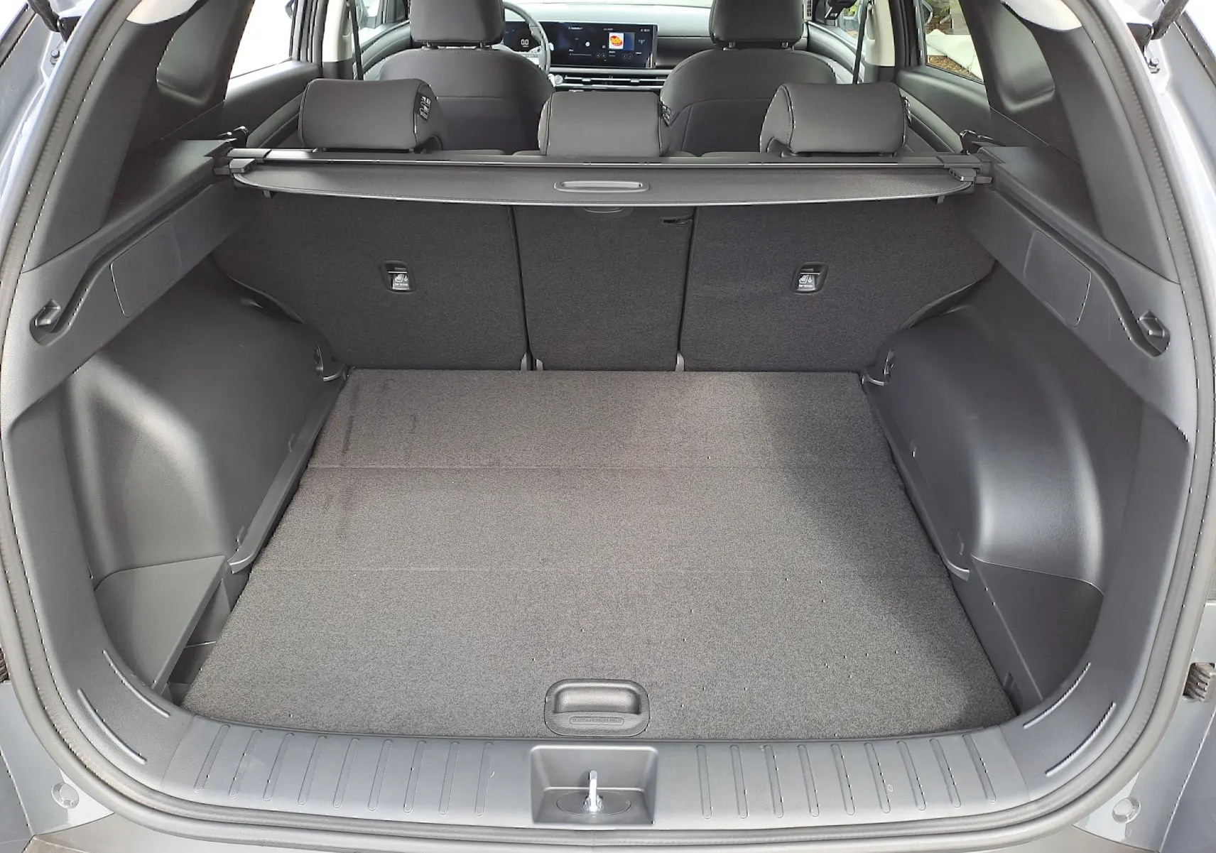 Coffre ouvert du Hyundai Tucson 2025 gris Ecotronic, vue arrière montrant l'espace de chargement et la banquette arrière noire.
